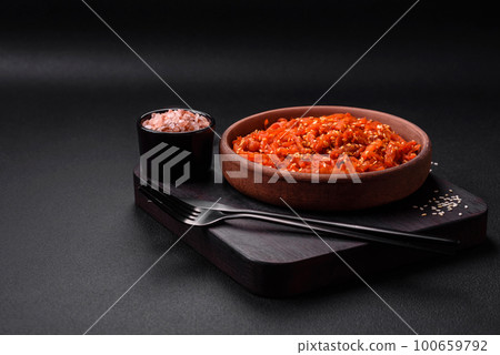 Dried squid chopped into slices and seasoned with sesame seeds and spices Dried squid chopped into slices and seasoned with sesame seeds and spices 100659792