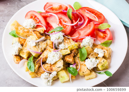 Fried zucchini with feta cheese, tomatoes, herbs and onions on a plate Fried zucchini with feta cheese, tomatoes, herbs and onions on a plate 100659899