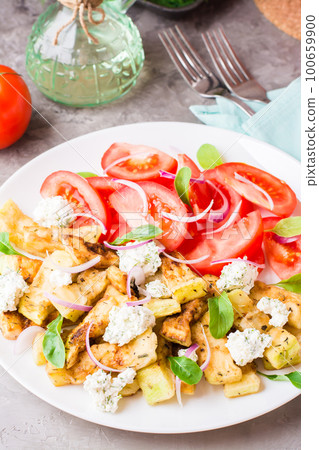 Fried zucchini with feta cheese, tomatoes, herbs and onions on a plate. Delicious appetizer ready to eat Fried zucchini with feta cheese, tomatoes, herbs and onions on a plate. Delicious appetizer ready to eat 100659900