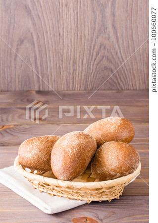 Fresh rye buns in a basket on a wooden table 100660077