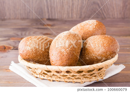 Fresh rye buns in a basket on a wooden table 100660079