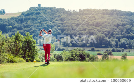 Golf player hitting ball long with driver 100660669