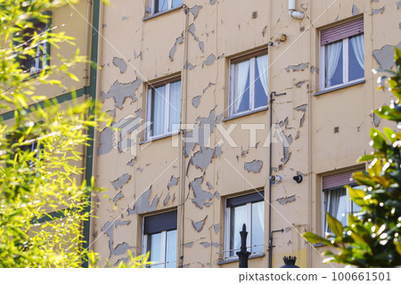 Damaged peeling paint on the wall of a residential building on a city street Damaged peeling paint on the wall of a residential building on a city street 100661501