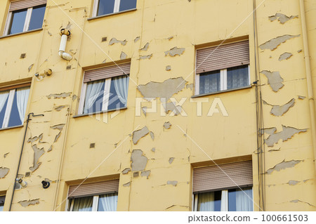 Damaged peeling paint on the wall of a residential building on a city street Damaged peeling paint on the wall of a residential building on a city street 100661503