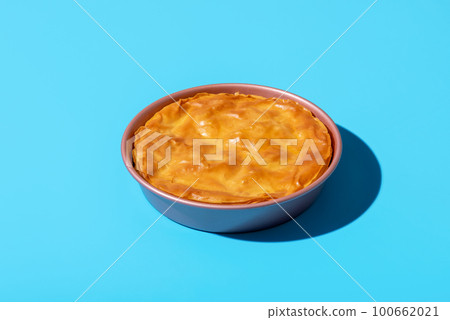 Balkan phyllo spinach cake isolated on a blue background. 100662021
