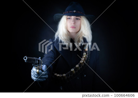 Old west blonde girl wearing black hat with revolver handgun 100664606