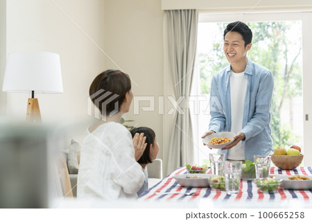 Family dining table image Father bringing food to the table 100665258