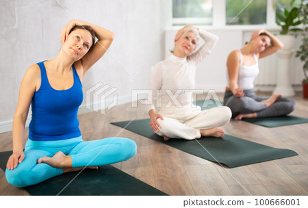 Adult woman doing yoga in fitness studio 100666001