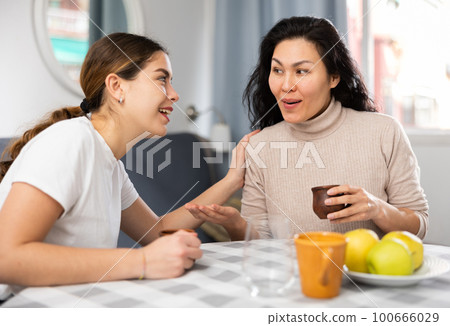 Two girlfriends talking resting at home 100666029