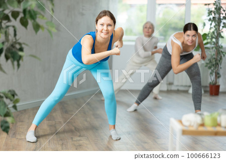Happy women doing aerobic dances together in dance studio 100666123