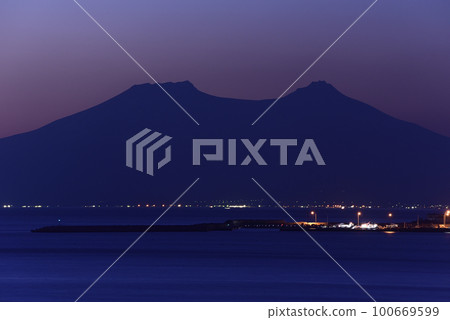 早春從北海道八雲町落邊拍攝日出時分的駒岳和石倉漁港的景色 100669599