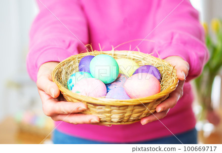 Close up of colorful Easter eggs in a basket. Female hands holding basket with colored Easter eggs. 100669717