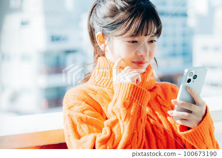 一個操作智能手機的年輕女子 100673190