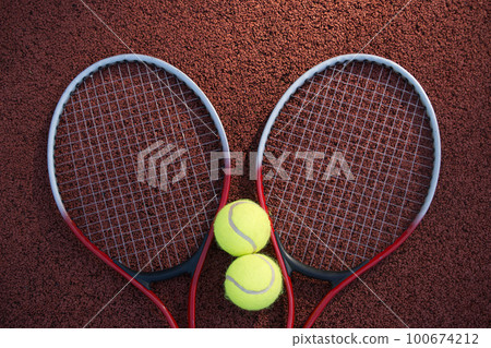 Two tennis balls and two racquets on tennis court 100674212