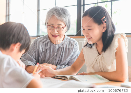 Elderly women and elementary school children who teach their grandchildren's summer vacation homework at home dining (homecoming / homecoming) 100676783