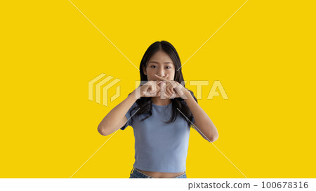 Asian woman doing silent gesture with finger, Noiseless symbol, Noisy mall, Hide a secret, Do not speak. shut your mouth, Noiseless signal transmission, Isolated on yellow background. Asian woman doing silent gesture with finger, Noiseless symbol, Noisy mall, Hide a secret, Do not speak. shut your mouth, Noiseless signal transmission, Isolated on yellow background. 100678316