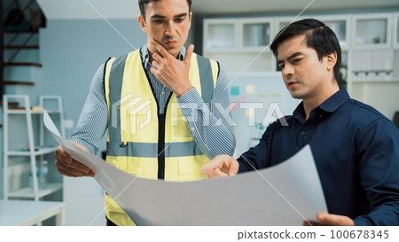 Competent investor investor discuss and brainstorm with engineers on blueprint. Competent investor investor discuss and brainstorm with engineers on blueprint. 100678345