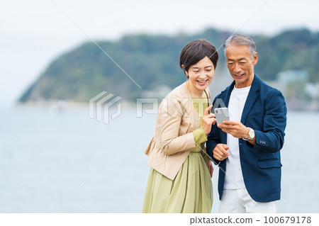 A middle-aged couple taking a commemorative photo with a smartphone 100679178