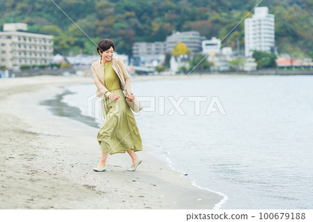 Middle-aged woman walking on the beach 100679188