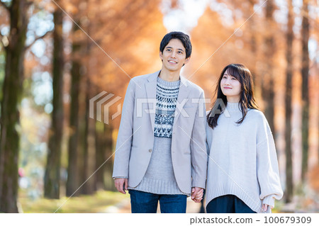 Young couple walking hand in hand along a tree-lined street Young couple walking hand in hand along a tree-lined street 100679309