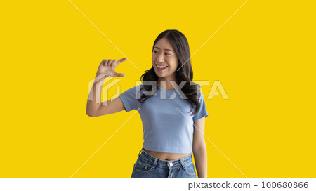 Asian woman with holding copyspace imaginary on the palm to insert an ad, Showing copyspace pointing, Showing her hand to present something on yellow background. 100680866