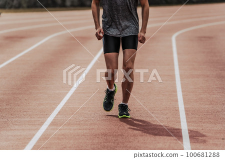 Male runner running straight on athletics track 100681288