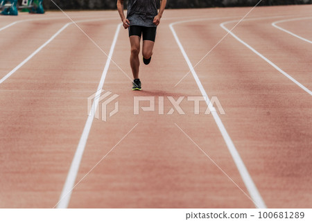 Male runner running straight on athletics track 100681289