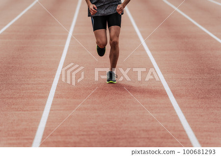 Male runner running straight on athletics track 100681293