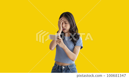 Young woman looking frustrated or depressed after losing playing games on mobile phone, Playing Games On Smartphone, Make an angry face and frown, Upset, Lost bet. 100681347