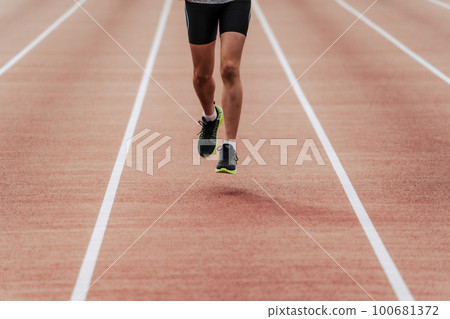 Male runner running straight on athletics track 100681372
