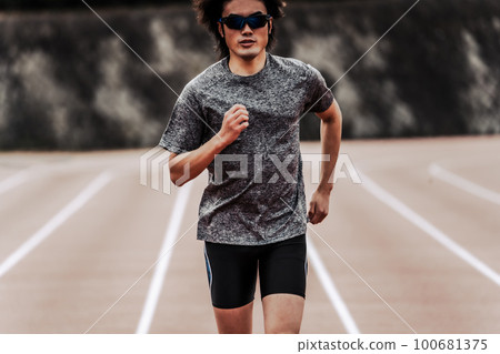 Male runner in sunglasses running in a straight line on an athletics track Male runner in sunglasses running in a straight line on an athletics track 100681375