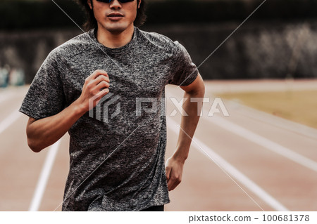 Male runner running straight on athletics track 100681378