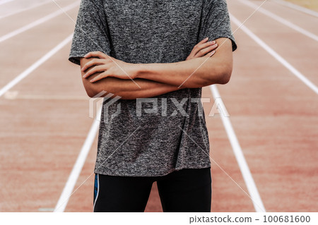 雙臂交叉在田徑跑道上的男賽跑者 雙臂交叉在田徑跑道上的男賽跑者 100681600