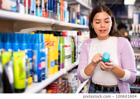 Pleasant woman is demonstraiting hair spray in hair care store Pleasant woman is demonstraiting hair spray in hair care store 100681604