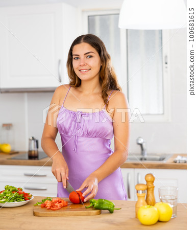 Young woman cooking vegetable salad in kitchen Young woman cooking vegetable salad in kitchen 100681615