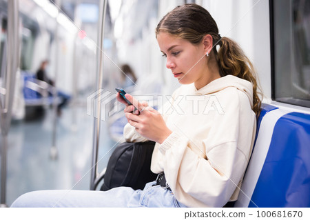 Portrait of woman holding smart phone in a subway train 100681670