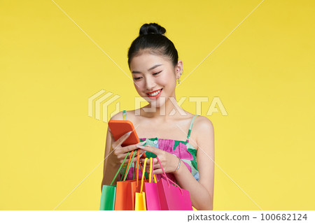 young woman holding shopping bags and smart phone young woman holding shopping bags and smart phone 100682124