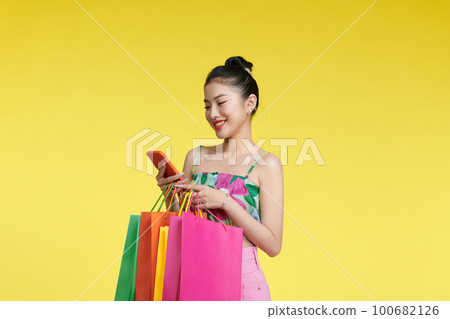 Portrait of a young woman using mobile phone with shopping bags in her hands. Portrait of a young woman using mobile phone with shopping bags in her hands. 100682126