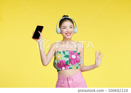 Young woman dancing while listening music with headphones and cellphone Young woman dancing while listening music with headphones and cellphone 100682128