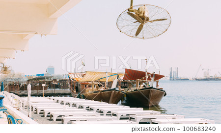 Many Dhow, sailboat, sailing vessel boat is moored to the city pier, jetty in sunny summer day. Urban city background. Port in Dubai, United Arab Emirates, UAE Many Dhow, sailboat, sailing vessel boat is moored to the city pier, jetty in sunny summer day. Urban city background. Port in Dubai, United Arab Emirates, UAE 100683240