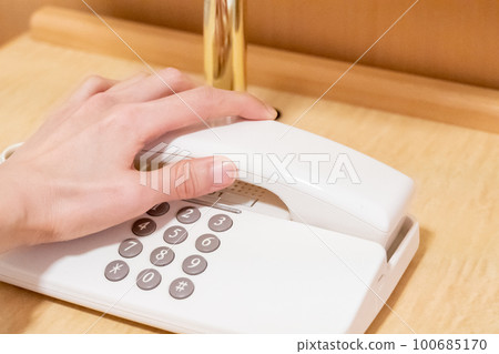 A woman's hand trying to make a phone call from a business hotel room 100685170