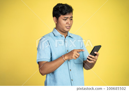 young Asian man shocked to see smartphone screen in isolated 100685502