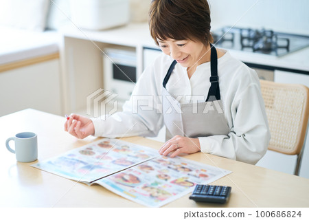 Woman looking at grocery advertisement Woman looking at grocery advertisement 100686824