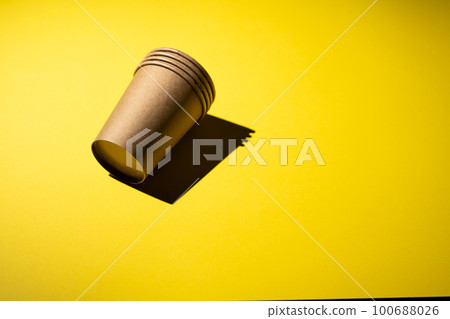 Cardboard coffee cup on yellow background with shadow. Cardboard coffee cup on yellow background with shadow. 100688026