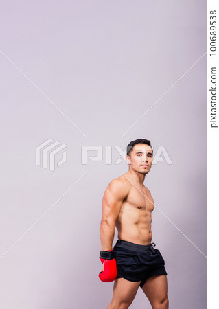 Muscular model sports young man in boxing gloves on grey background. Male flexing his muscles. 100689538