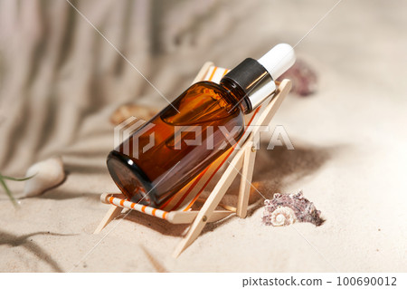 Summer sunscreen essence in deck chair on the sand backgroundwith shells ans seastar. B Summer sunscreen essence in deck chair on the sand backgroundwith shells ans seastar. B 100690012