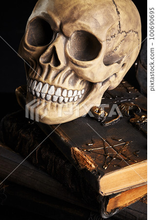 Realistic model of a human skull with teeth on a wooden dark table, black background. Medical science or Halloween horror concept. Close-up shot. Realistic model of a human skull with teeth on a wooden dark table, black background. Medical science or Halloween horror concept. Close-up shot. 100690695