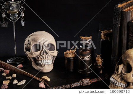 Realistic model of a human skull with teeth on a wooden dark table, black background. Medical science or Halloween horror concept. Close-up shot. 100690713