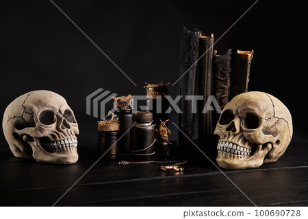 Realistic model of a human skull with teeth on a wooden dark table, black background. Medical science or Halloween horror concept. Close-up shot. Realistic model of a human skull with teeth on a wooden dark table, black background. Medical science or Halloween horror concept. Close-up shot. 100690728