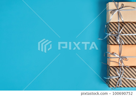 Different sizes, striped and plain paper gift boxes tied with ribbons and bows on a blue background. Close-up, copy space, top view. Different sizes, striped and plain paper gift boxes tied with ribbons and bows on a blue background. Close-up, copy space, top view. 100690752